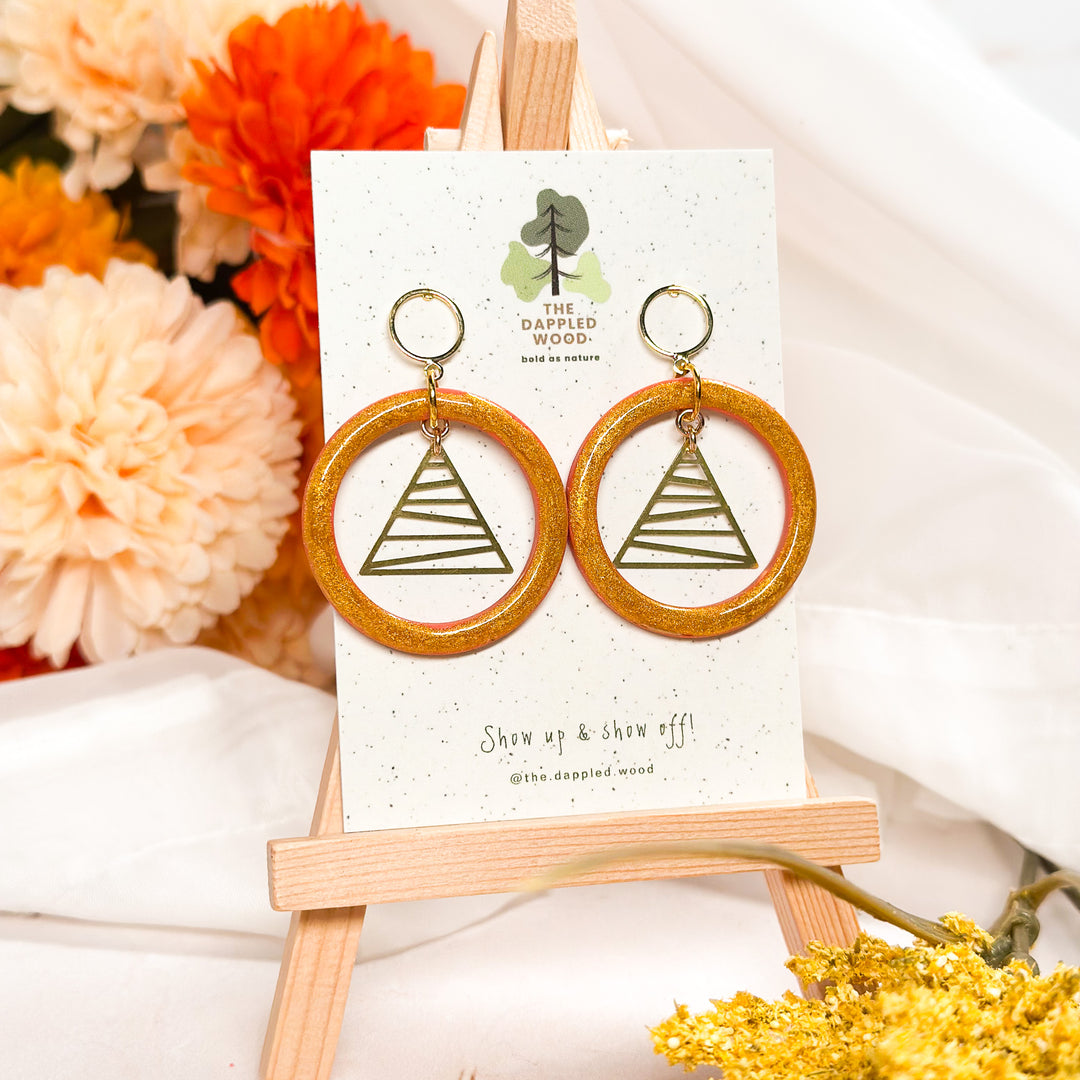 Gold-painted hollow circle earrings with a triangle charm, modern geometric fall jewelry by The Dappled Wood.