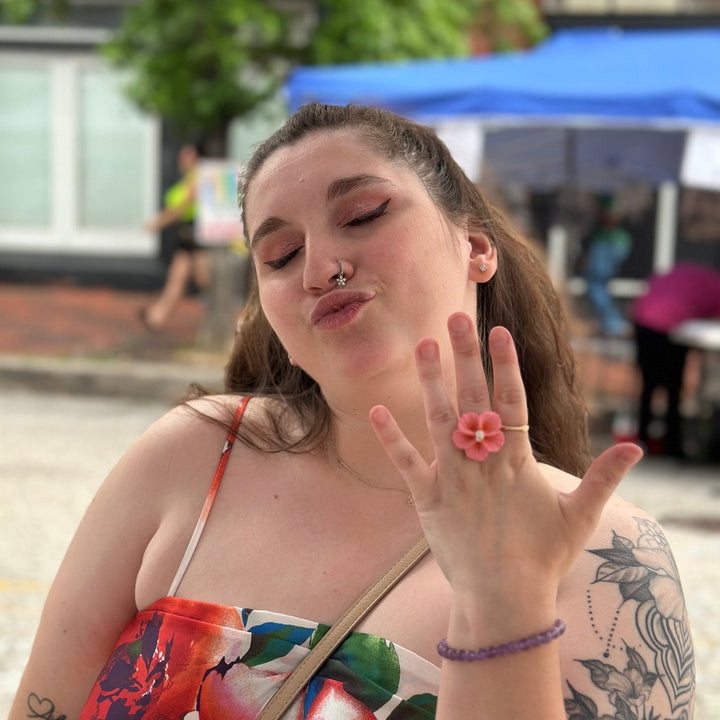 Customer showing The Dappled Wood Isadora flower ring in pastel pink at an outdoor market.