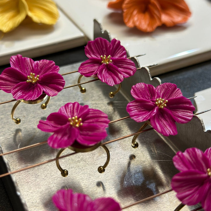 Fuchsia Isadora flower rings by The Dappled Wood displayed on gold plated stainless steel adjustable bands during the baking process.