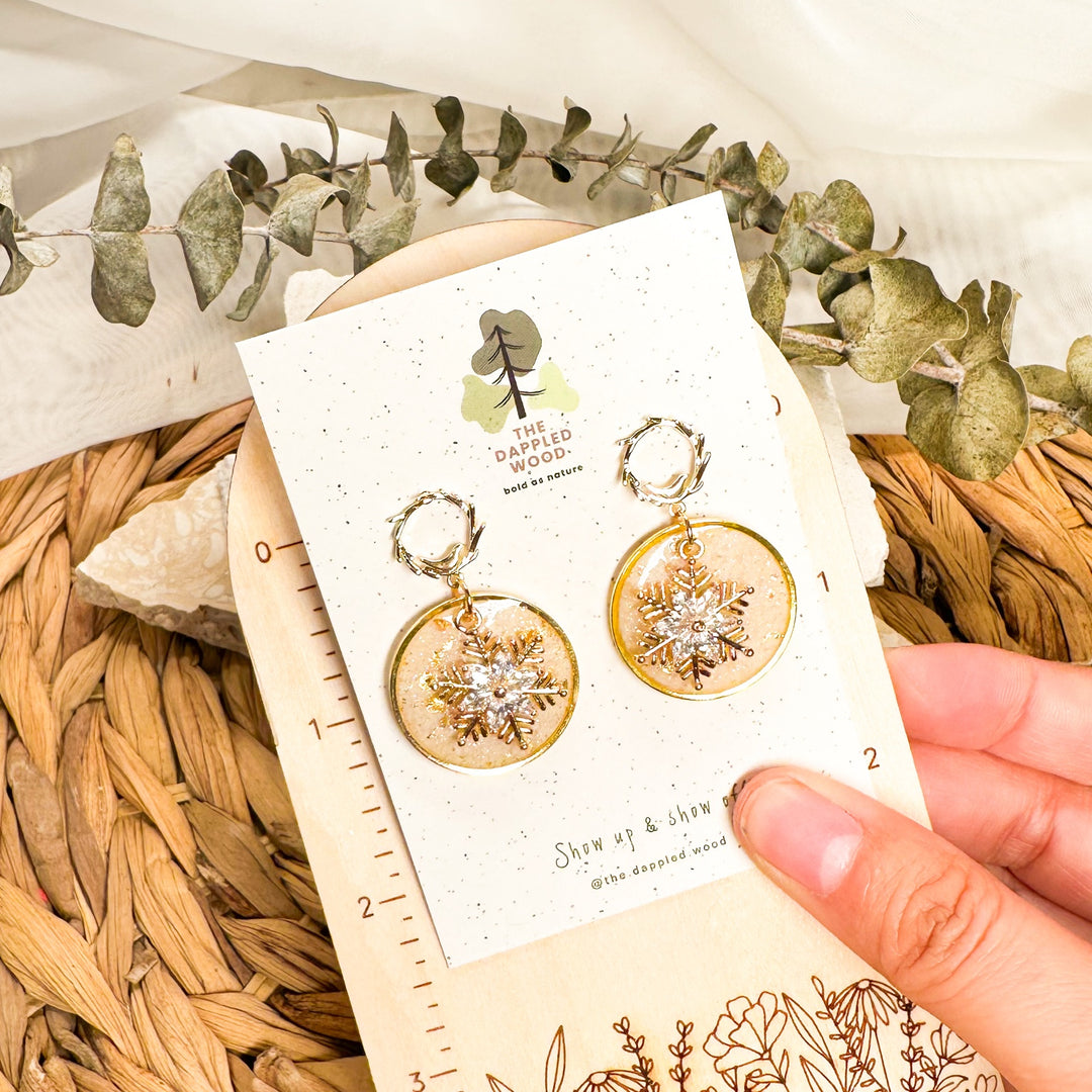 Judy snowflake dangle earrings displayed beside an inch ruler for size reference.