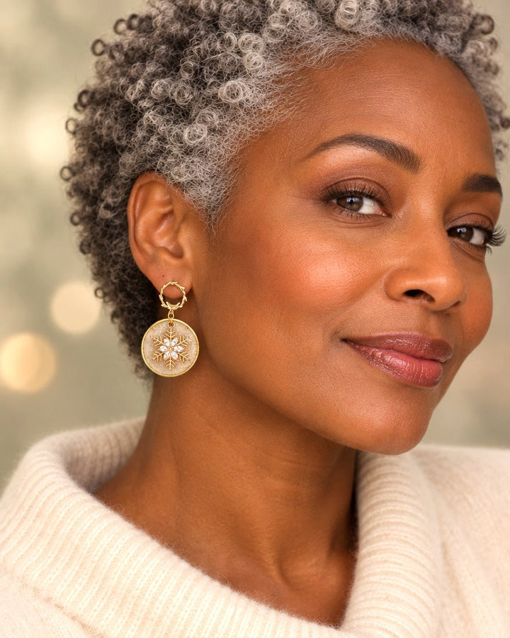 Model wearing Judy circular champagne and gold snowflake dangle earring in a warm studio setting