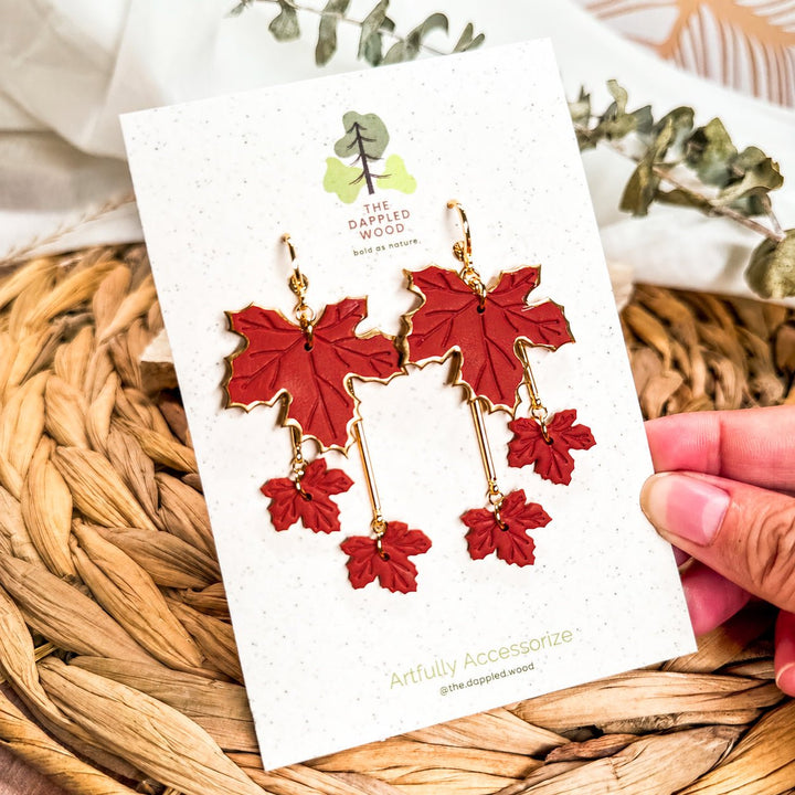 Laurel tiered maple leaf earrings in brick red displayed on a The Dappled Wood card.