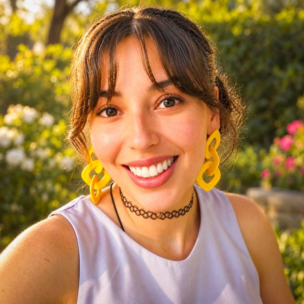Model outdoors wearing bright yellow Lexa XL chain link statement earrings