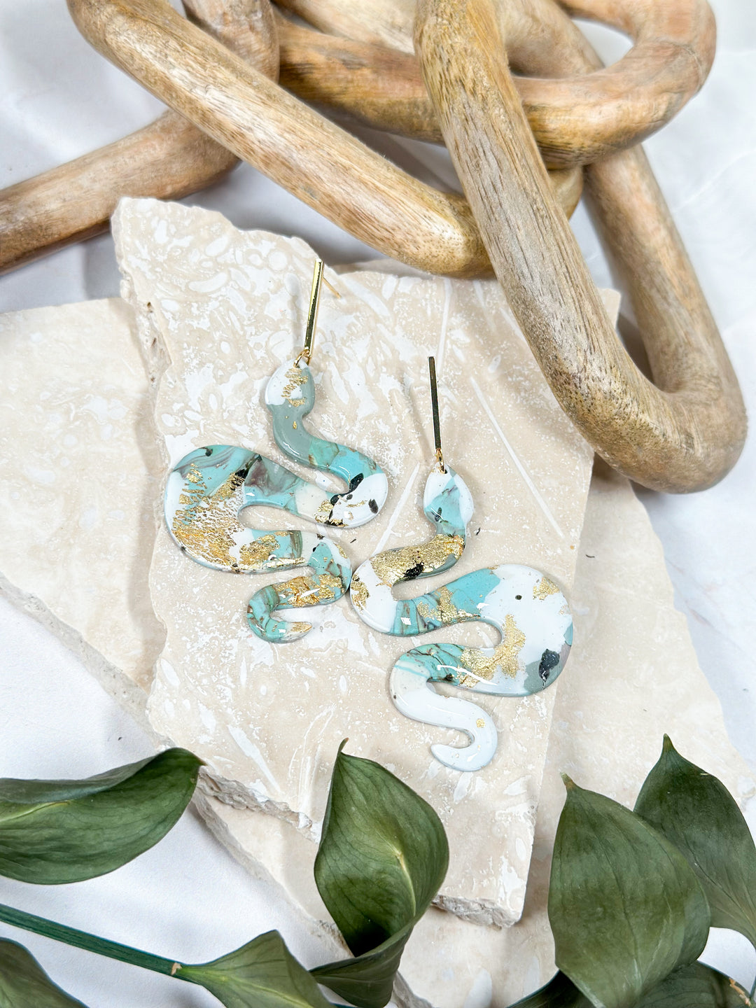 The Dappled Wood Lilith Collection snake earrings in Dusty Turquoise. Hypoallergenic statement earrings featuring a blend of muted turquoise and white marbling with gold details.