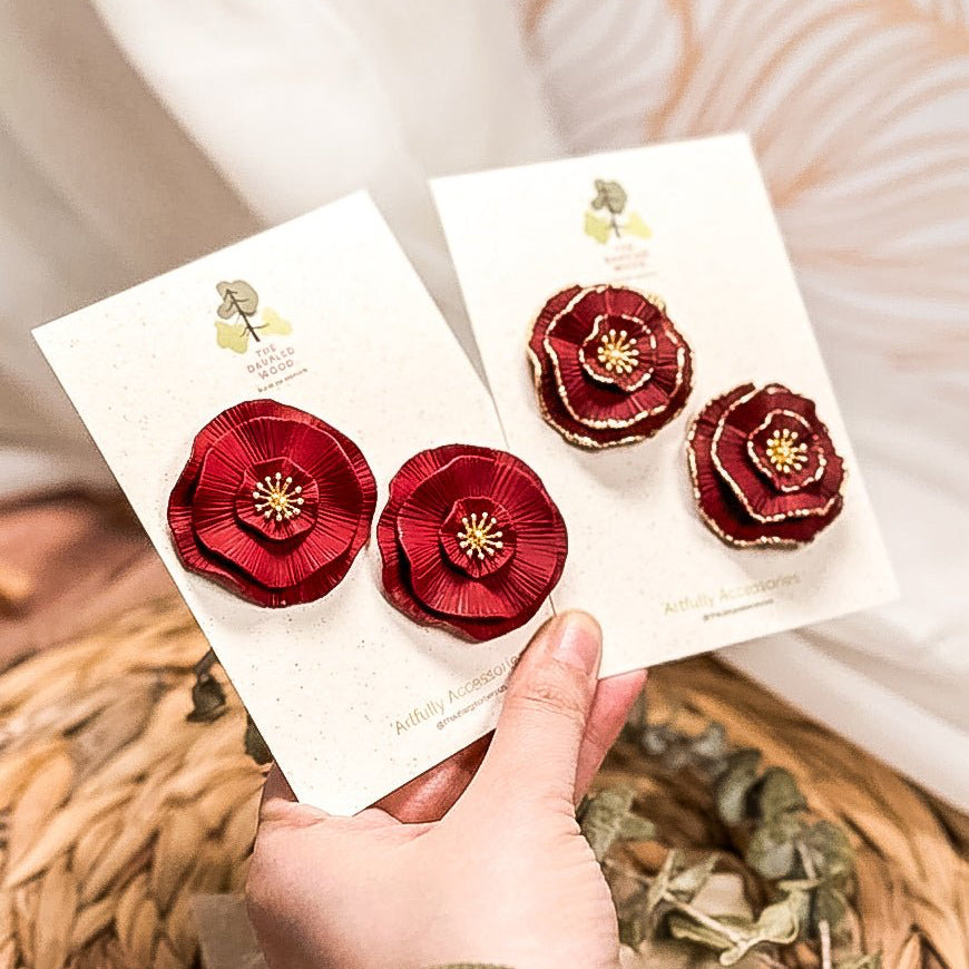 Luisa circular floral stud earrings with layered red petals and dimensional gold centers.