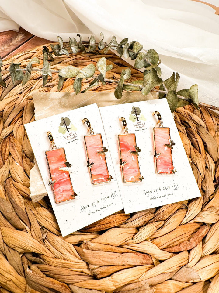 Marisol faux rose quartz earrings with rectangular pink drops, gold frames, and butterflies.