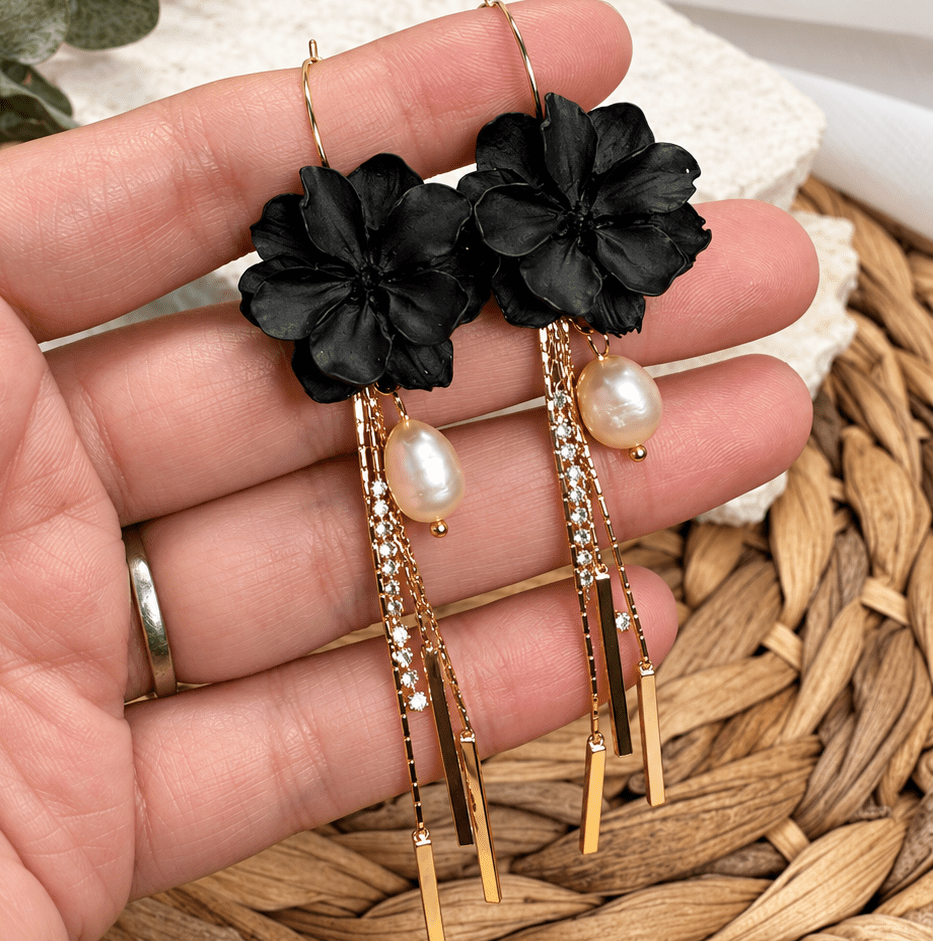 Close-up of black Maritza flower earrings with freshwater pearls, gold tassels, and crystal details.