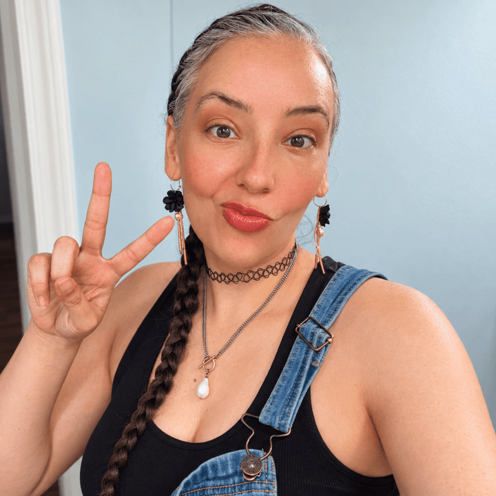 Customer wearing black Maritza flower earrings with freshwater pearls and gold tassels.