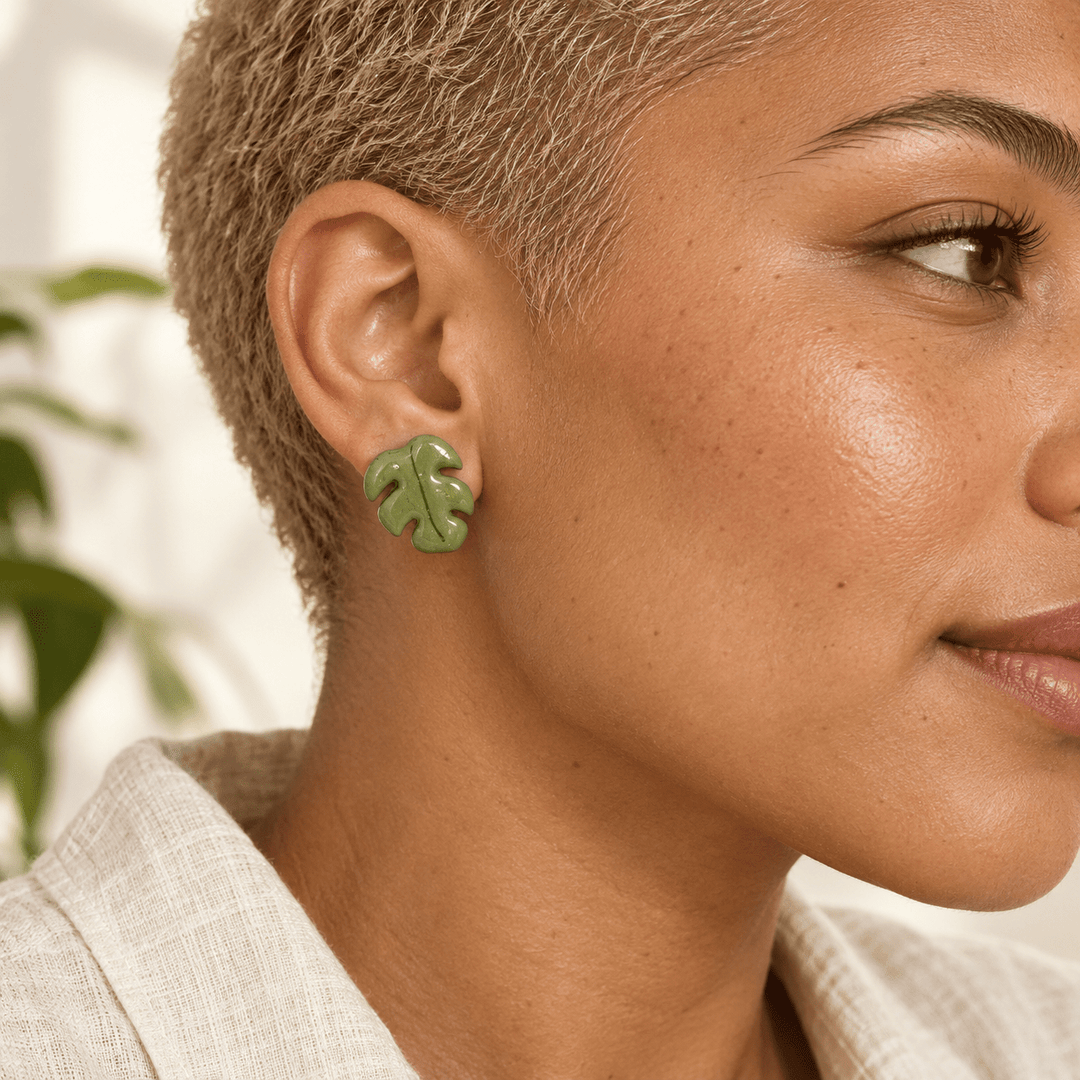 AI-generated styling preview of Marnie Monstera leaf stud earrings on a model with a blonde buzzcut; scale illustrative.