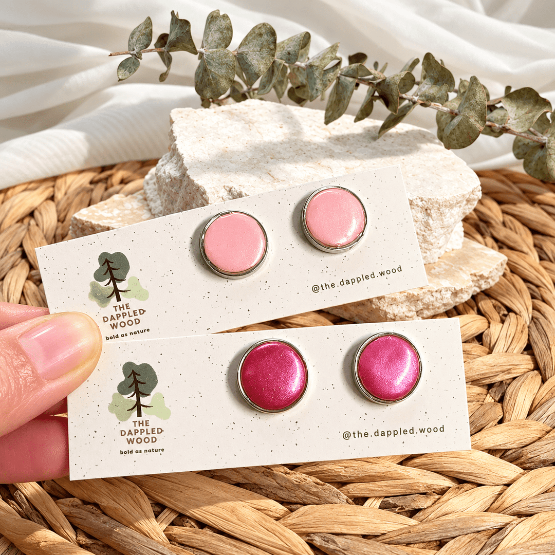 Nerine pearl shimmer bezel studs in pastel pink and fuchsia with silver-tone rims on cards.