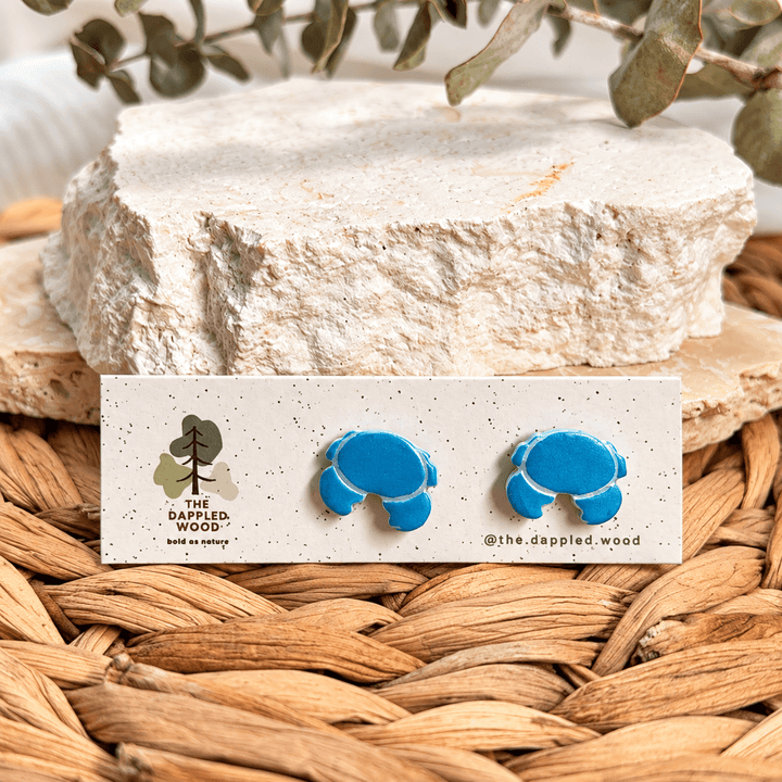 Nerissa blue crab stud earrings with silver edging on a display card.
