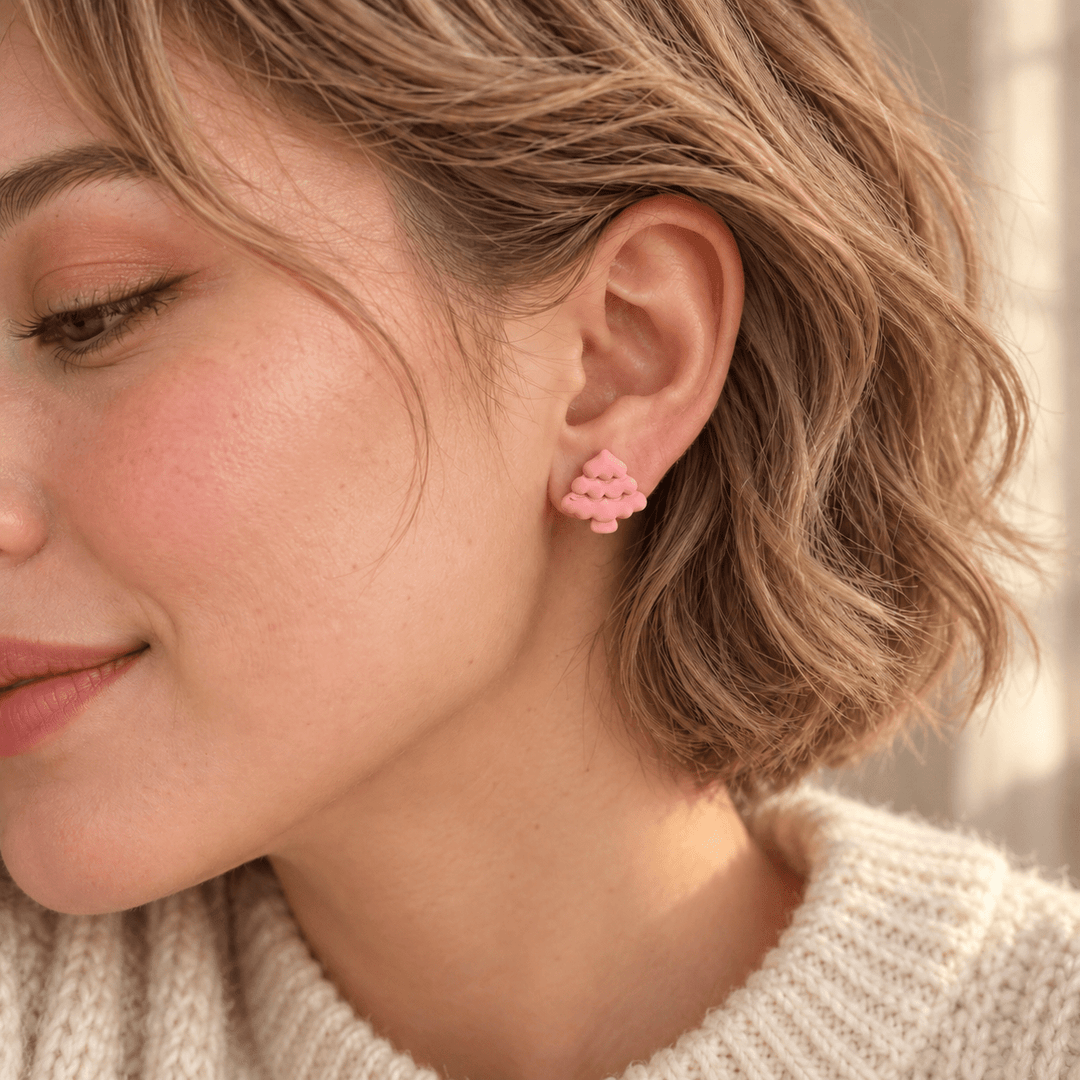 AI-generated styling preview of Noella pastel pink Christmas tree studs on a model with natural blonde waves; scale illustrative.