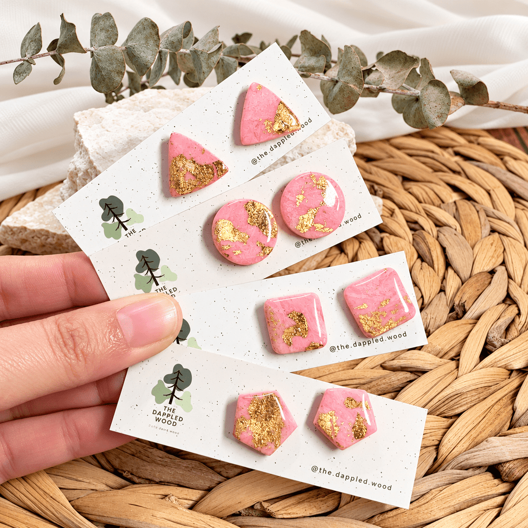 Four pairs of Odette pink marbled gold leaf studs displayed on earring cards