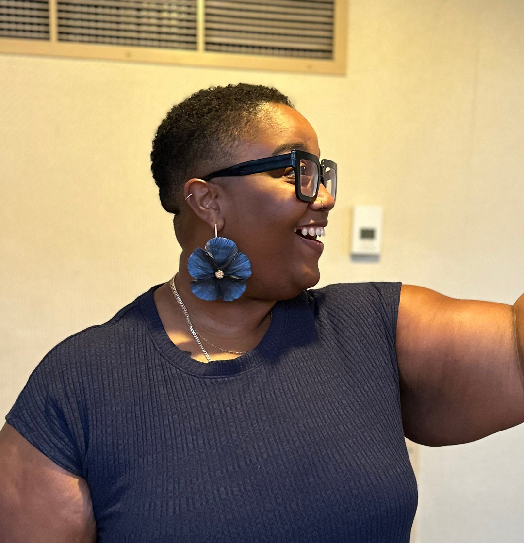 Customer wearing the Sabine earrings in Midnight by The Dappled Wood, showcasing bold navy petal inspired statement drops in a warm indoor setting that highlights the design.