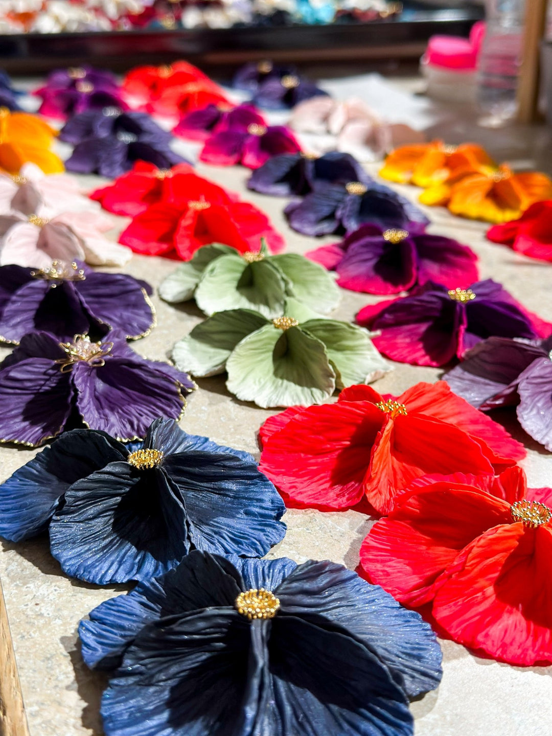 Assorted Sabine earrings by The Dappled Wood arranged in rows of vibrant colors, highlighting the handcrafted petal inspired statement design in bright natural light.