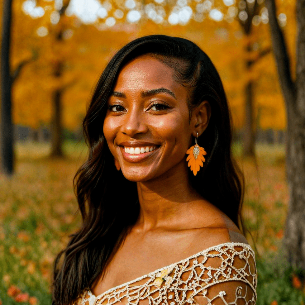 Model wearing the Solana earrings in Sunflower Yellow by The Dappled Wood, featuring bright yellow leaves with gold accents styled outdoors among fall trees and warm golden light.