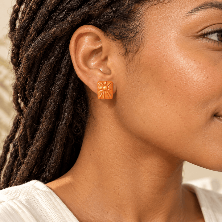 AI-generated styling preview of a model with dark locs wearing a Soleil sunburst stud; scale is illustrative