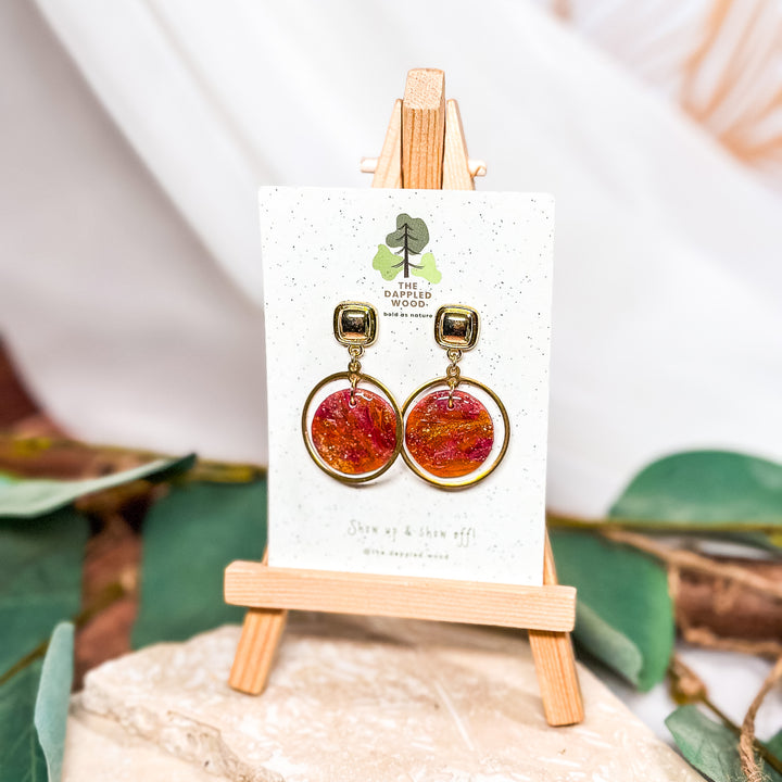 The Dappled Wood Oakley one-of-a-kind statement earrings from the Spring 2024 collection featuring an amber, fuchsia swirl polymer clay design, suitable for sensitive ears.