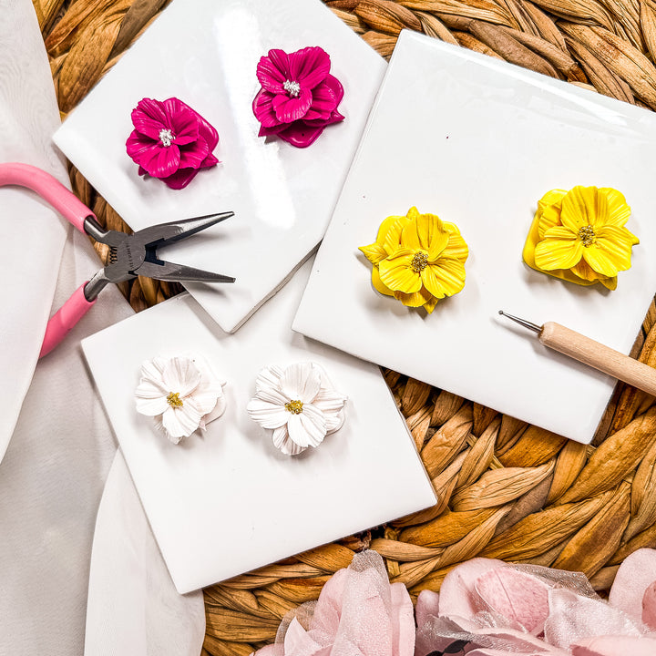 A flat lay of a collection of spring flower earrings and clay tools for promoting the The Dappled Wood's Flora & Flow earrings workshop and watercolor class.