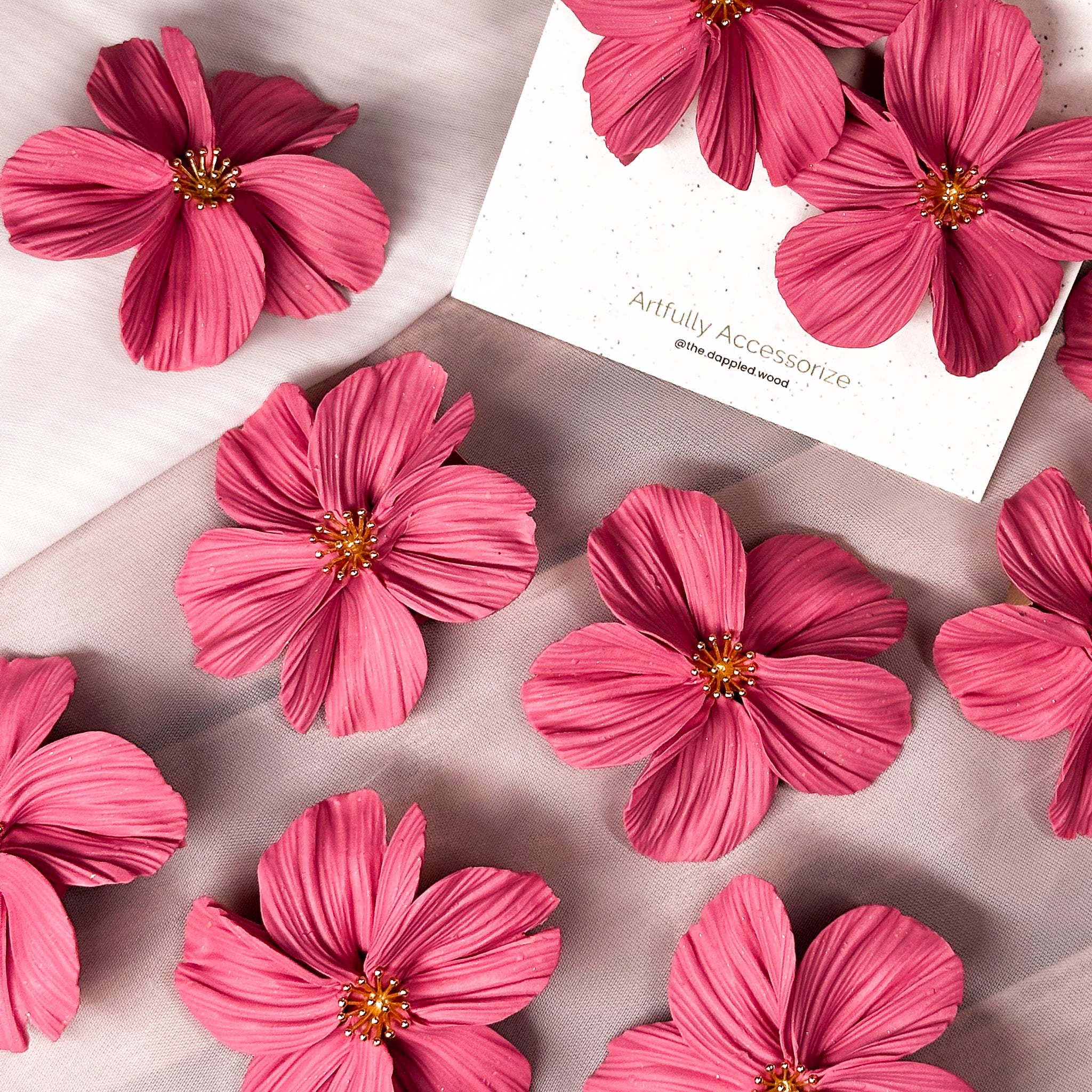 A flat lay image of a collection of bubble gum pink flower earrings from The Dappled Wood Spring 2025 collection.