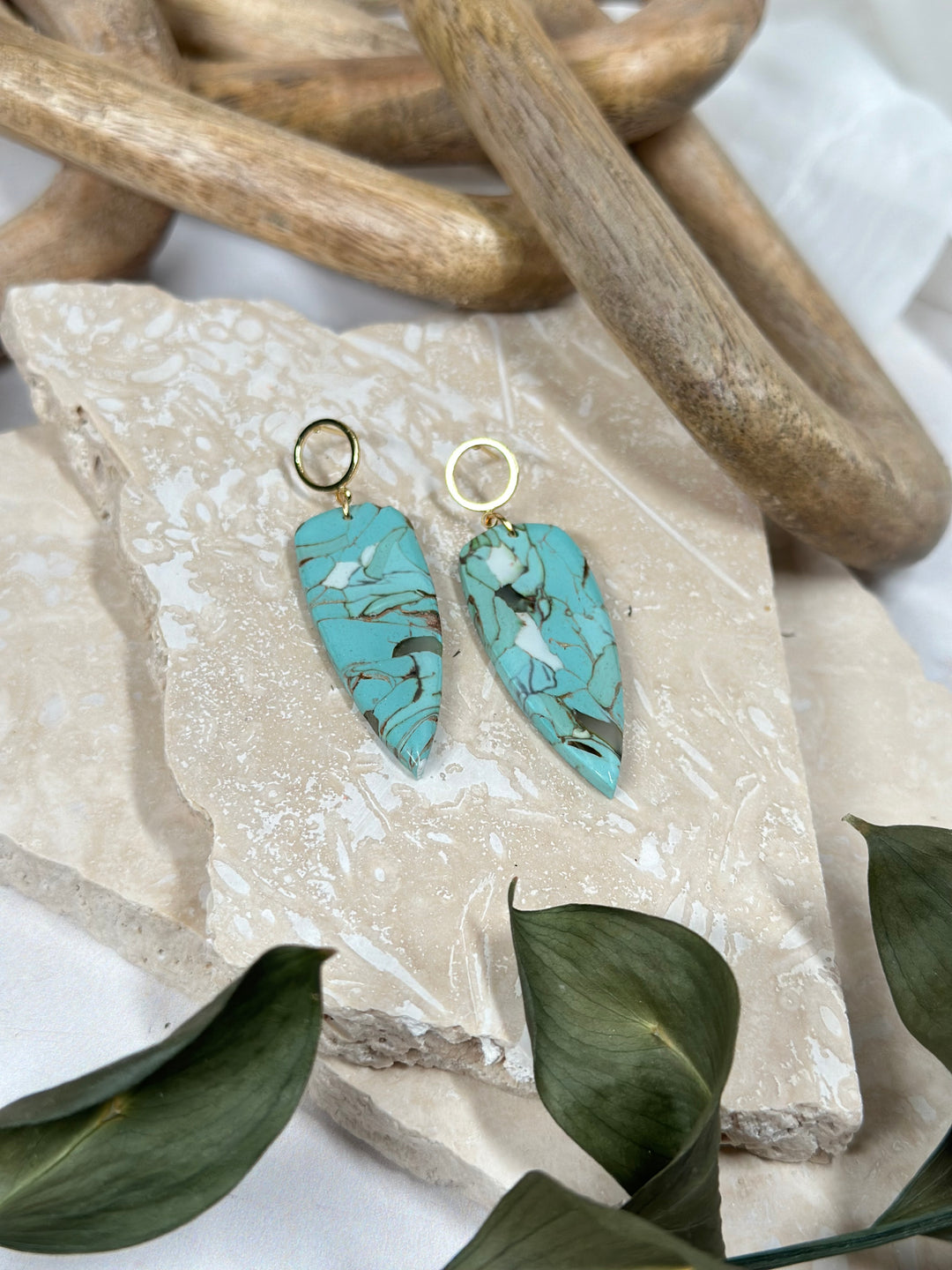 A variation of Dusty Turquoise earrings featuring a faux stone dagger with hollow gold circle posts. Handmade statement jewelry for summer 2024.