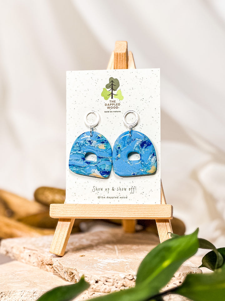 Light blue earrings with a gumdrop-shaped design, featuring a hollow circle steel post. A vibrant addition to any jewelry collection inspired by larimar earrings. Part of The Dappled Wood's Poolside collection from summer 2024.