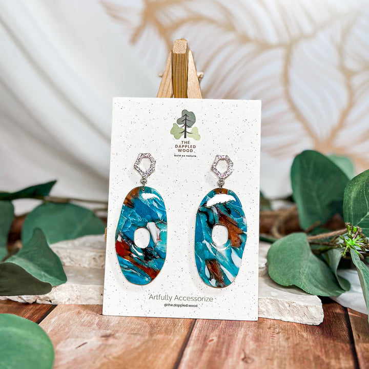 The Dappled Wood Tide Pool ocean stone earrings from the Summer 2024 collection featuring a large donut-shaped polymer clay design, offering a bold statement for sensitive ears.