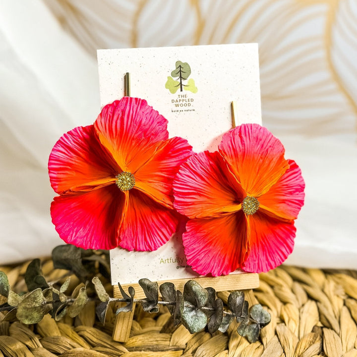 The Dappled Wood's Sabine polymer clay flower earrings in Hibiscus feature a vivid tropical orange to pink gradient. Bold floral clay earrings and lightweight statement jewelry, perfect for resort wear or summer getaways.