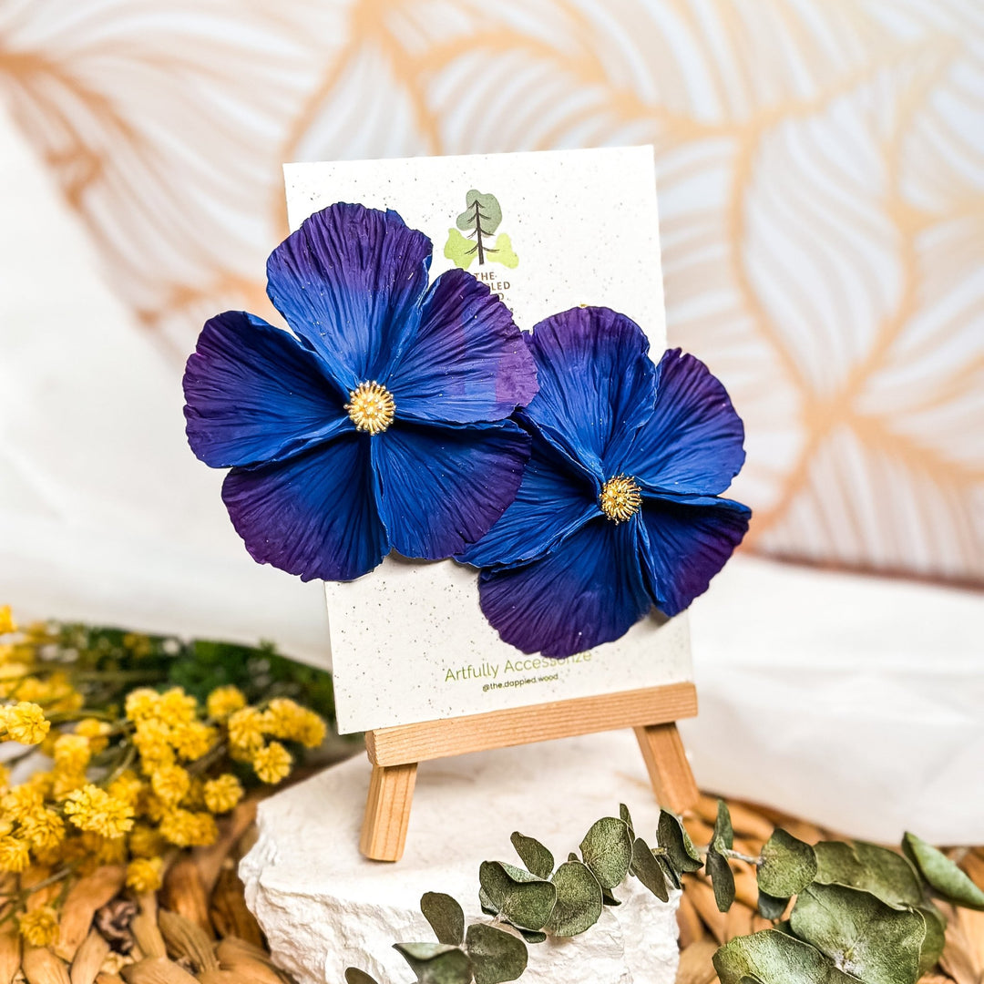 The Dappled Wood's Sabine polymer clay flower earrings in Indigo feature a deep blue to violet hue. Bold floral clay earrings and lightweight statement jewelry, perfect for creative gatherings or moody fall styling.