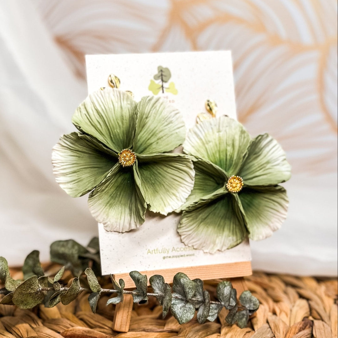 The Dappled Wood's Sabine polymer clay flower earrings in Sage feature a dusty sage green to white gradient. Bold floral clay earrings and lightweight statement jewelry, perfect for nature-inspired events or casual outdoor gatherings.
