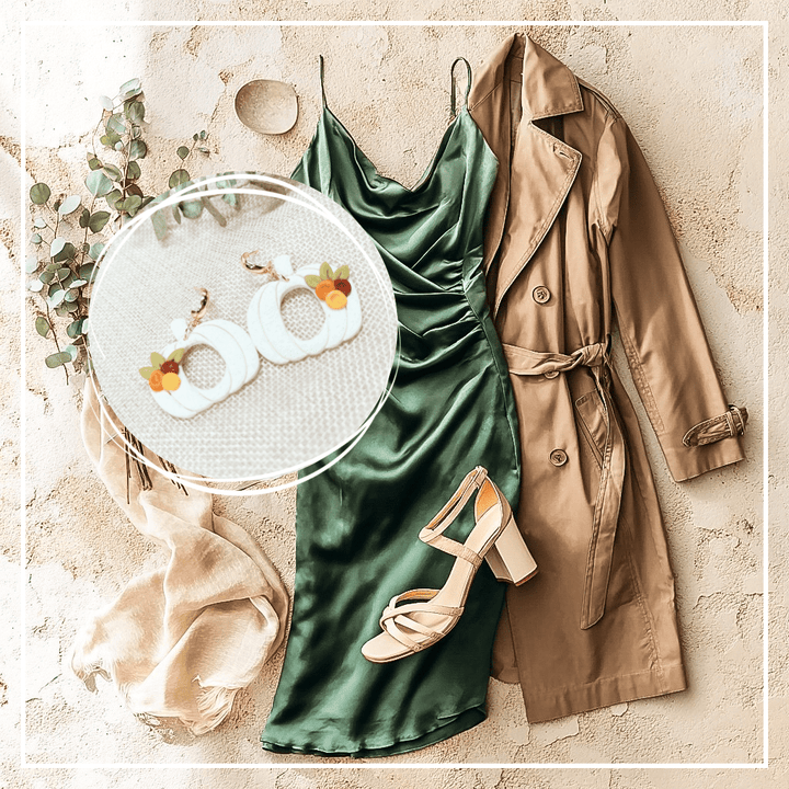 Fall wedding outfit inspiration featuring the Sylvia pumpkin earrings from The Dappled Wood. White pumpkin hoop earrings highlighted over a styled flatlay with a green satin dress, trench coat, heels, scarf, and greenery.