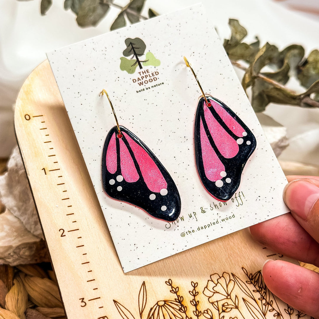 Pink Winged Whispers faux butterfly wing earrings shown beside a ruler for a 2.25-inch size reference by The Dappled Wood.