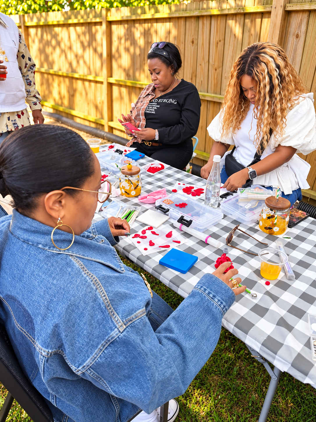 Guests creating polymer clay flowers together during a sunny outdoor class