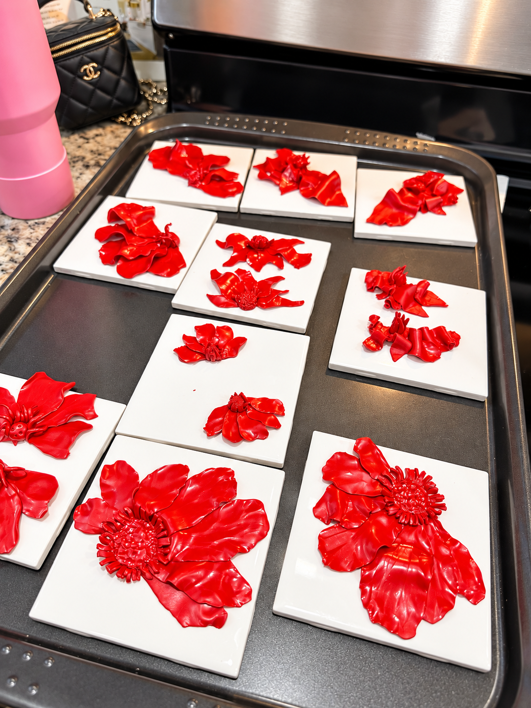 Red polymer clay flowers drying on ceramic tiles during a hands-on earring workshop
